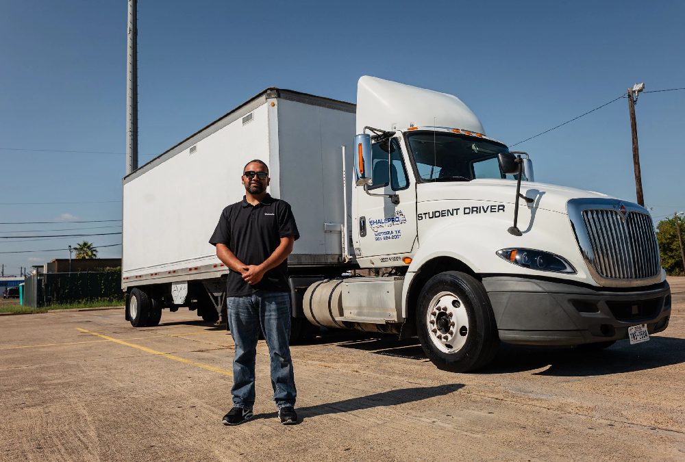 Man standing confidently in front of a large delivery truck.
