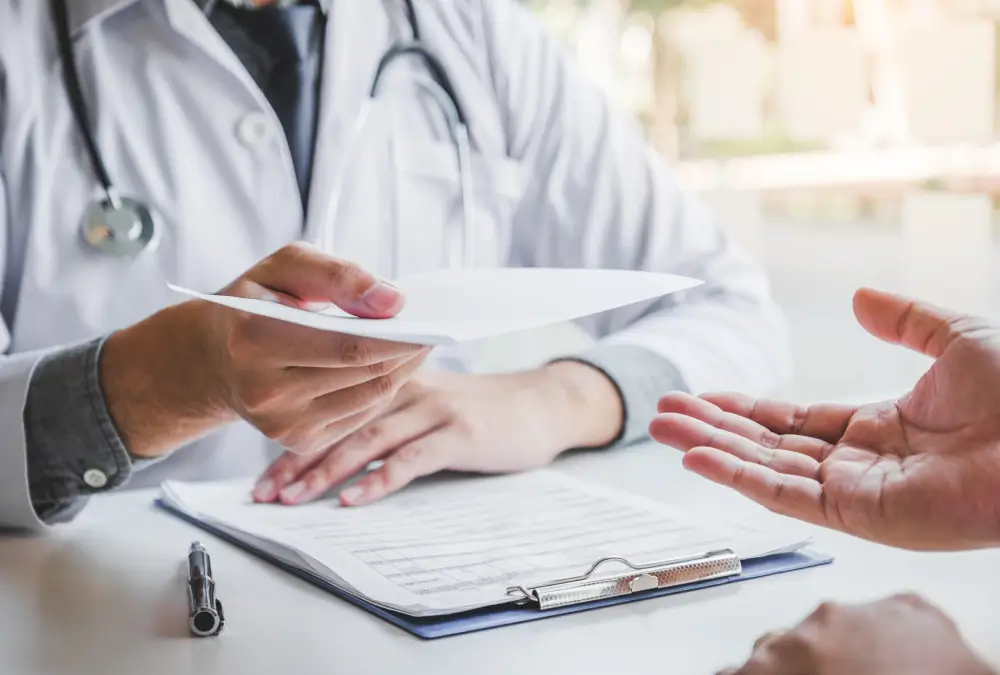 Doctor handing document to patient across table.