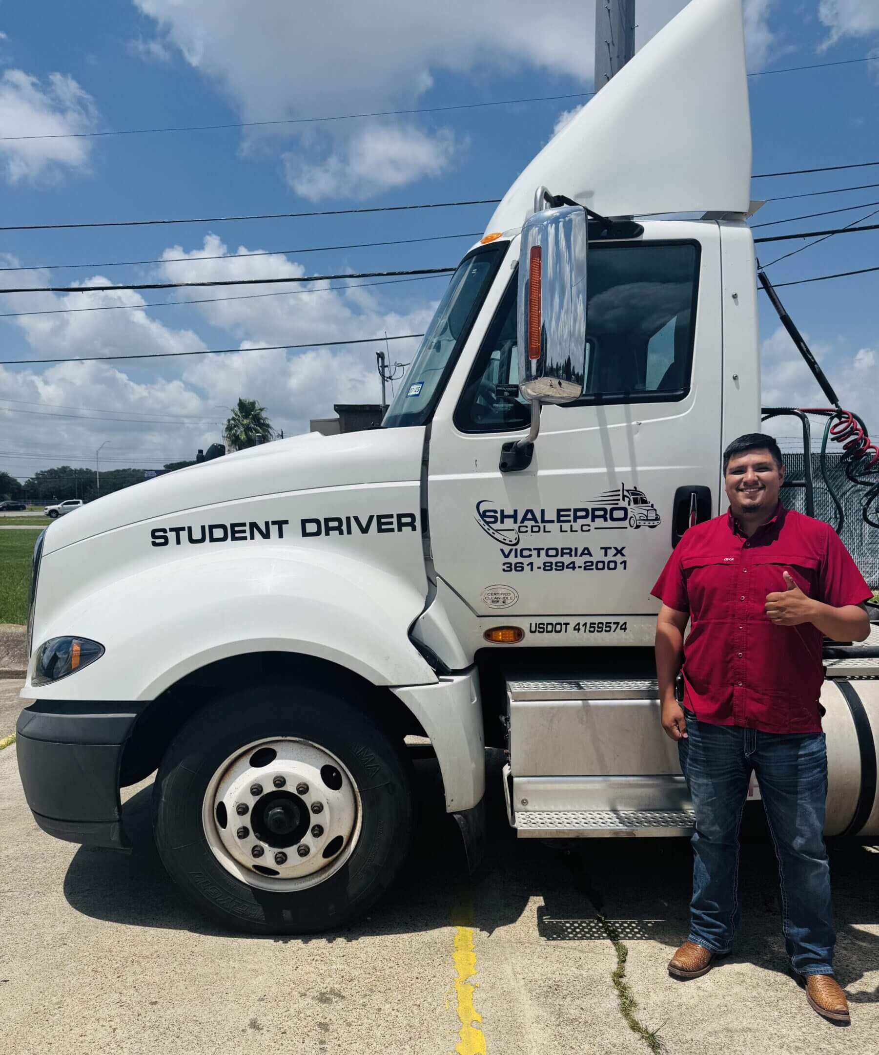 Man standing beside a white truck labeled 'Student Driver' on a sunny day.