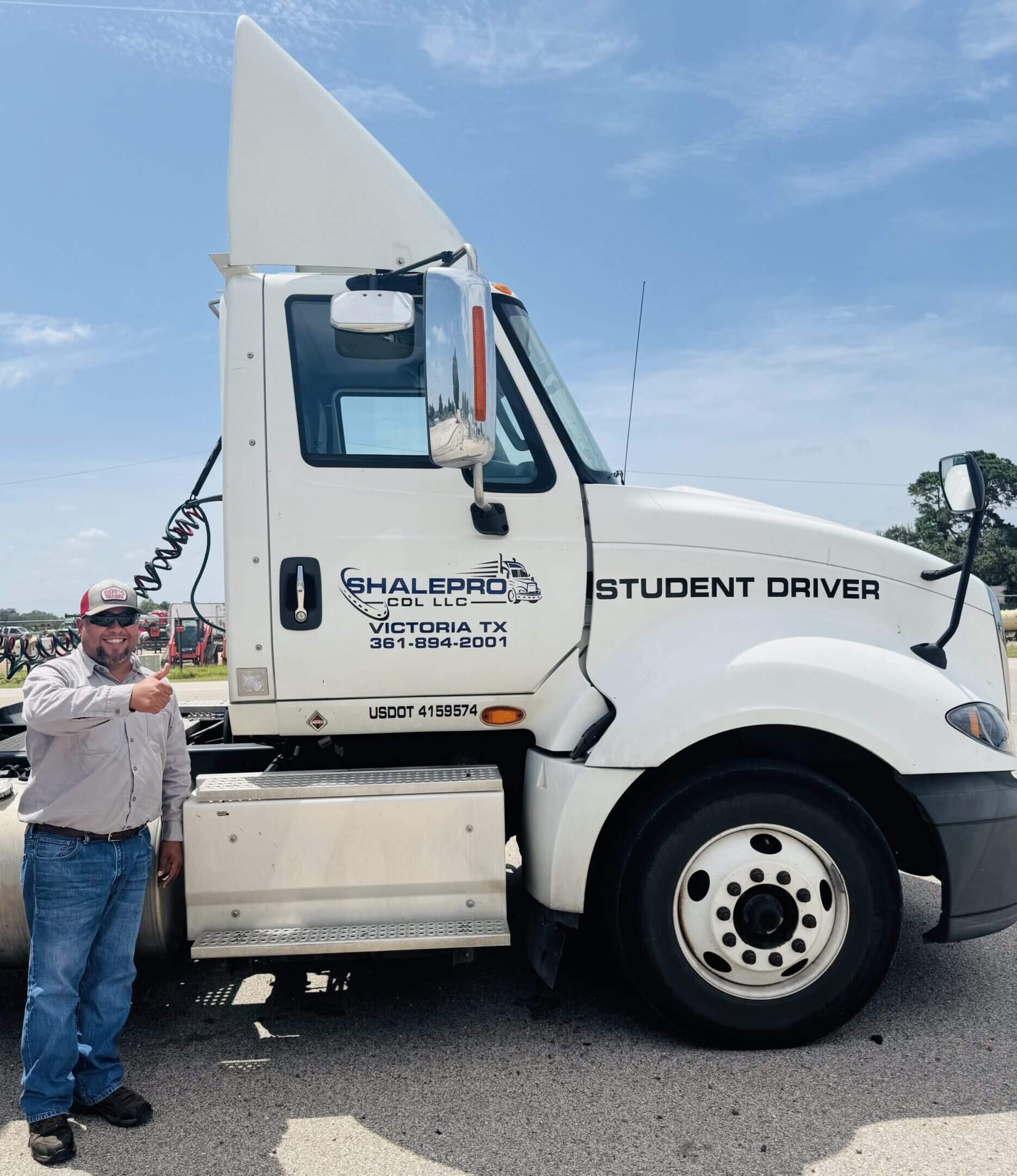 A student driver truck with a person standing beside it giving a thumbs up.