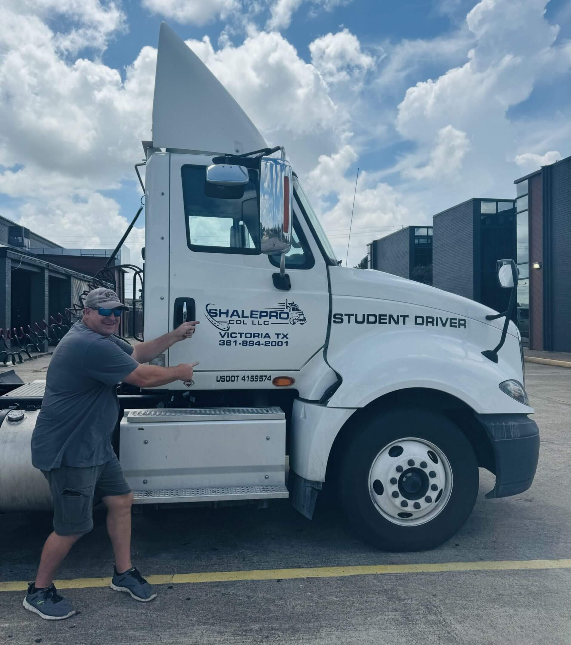 Man standing next to a large white truck labeled 'Student Driver'.