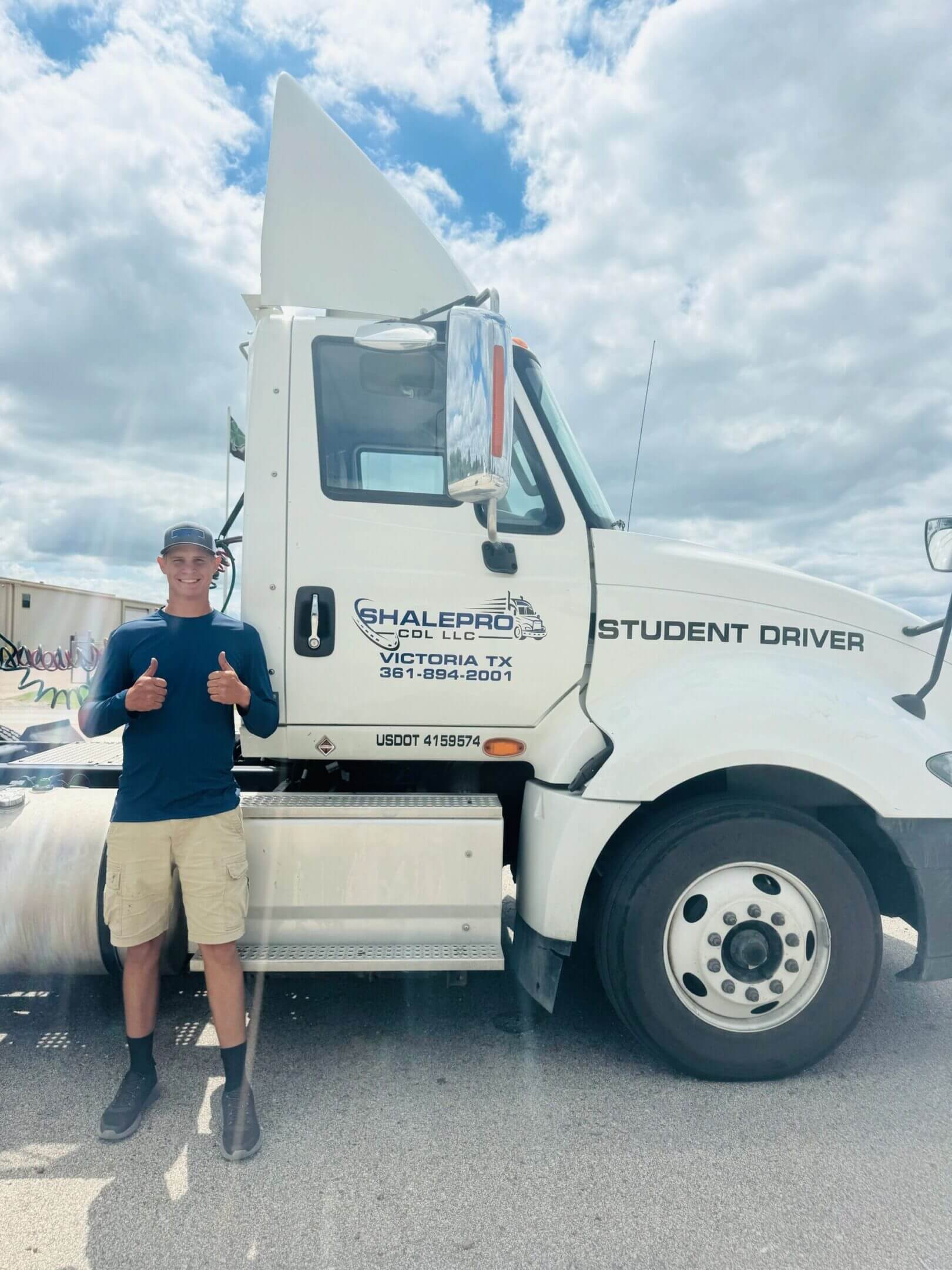 Young man giving thumbs up next to a student driver truck.