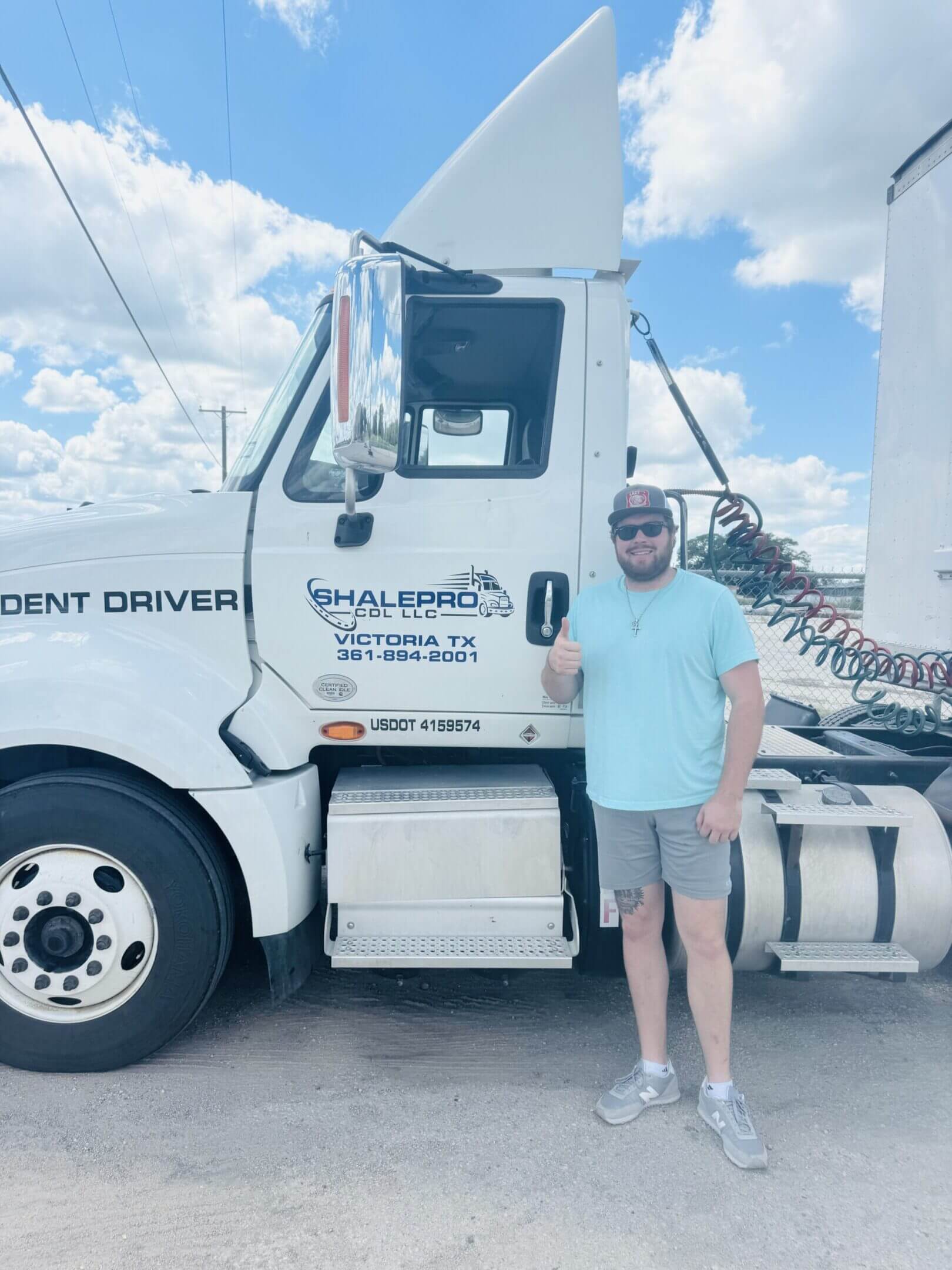 Man standing in front of a white semi-truck with company branding.