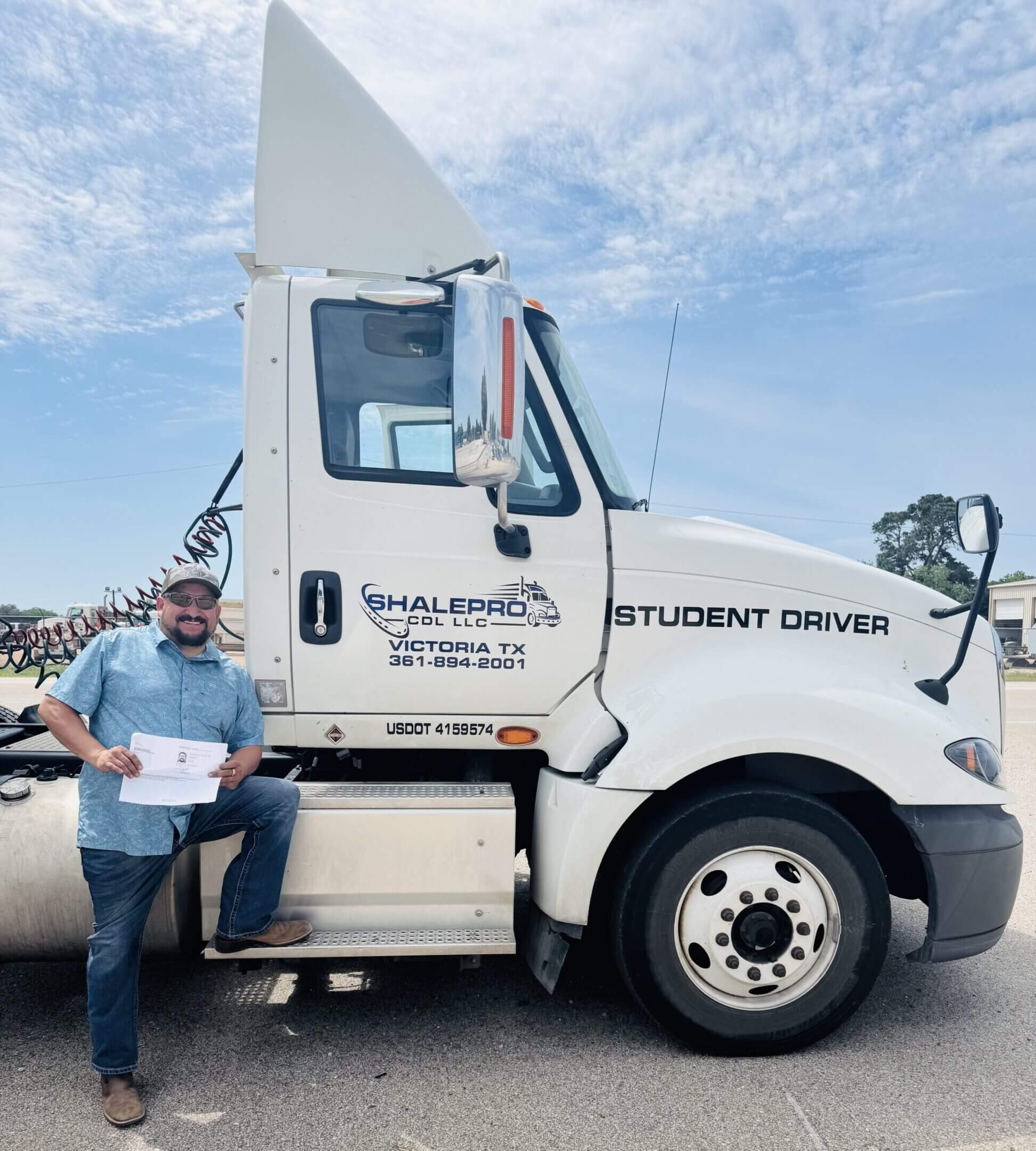 Person standing next to a white student driver truck holding a document.